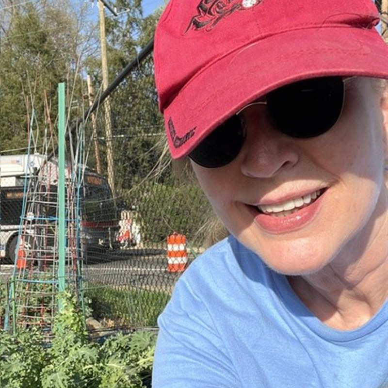 Marti, the writer behind Mailbox 4143, smiling in a community garden.