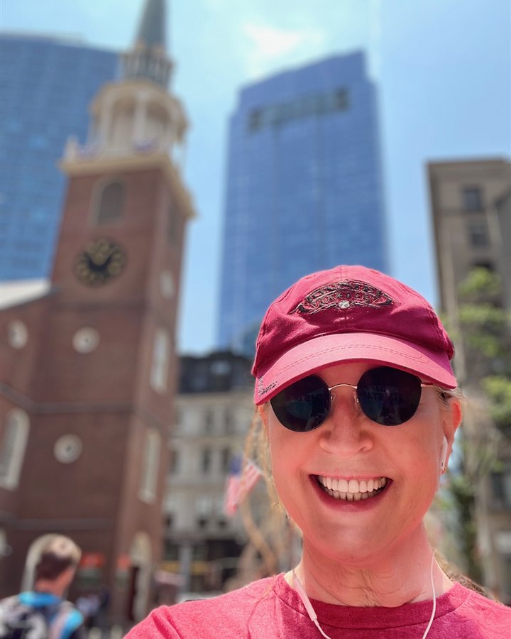 Smiling in front of a historic clocktower on a solo city walk — an 'In the Wild' moment.